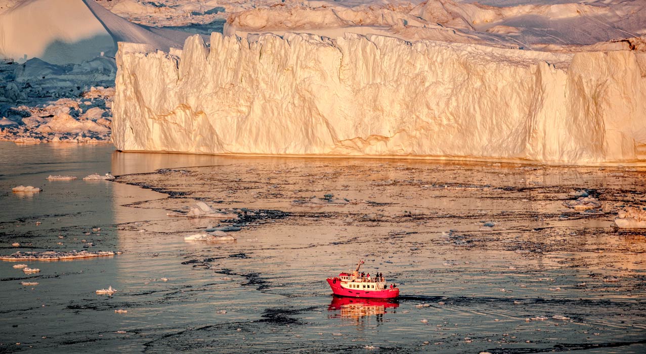Bootsfahrt während Grönlandreise im Fjord vor riesigen Eisbergen in Grönland